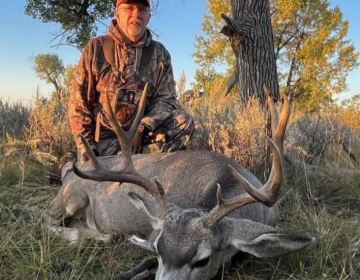A happy  hunter with his mule deer near a cottonwood tree in Northeastern Wyoming.